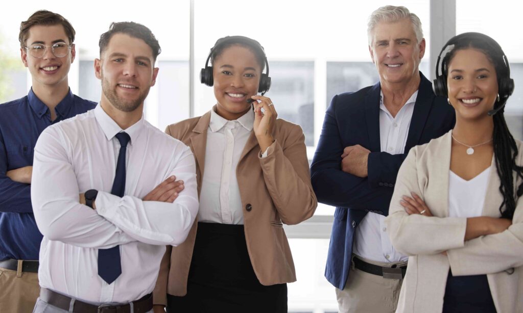 A diverse team of five insurance agents and call center representatives smiling for a group portrait, highlighting professionalism and strong customer experience for insurance services.